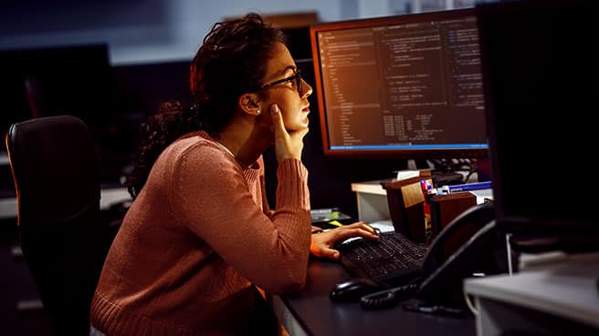 Kvinnelig IT-student foran en skjerm med kodespråk