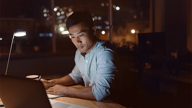 man sitting at night in front of a laptop working